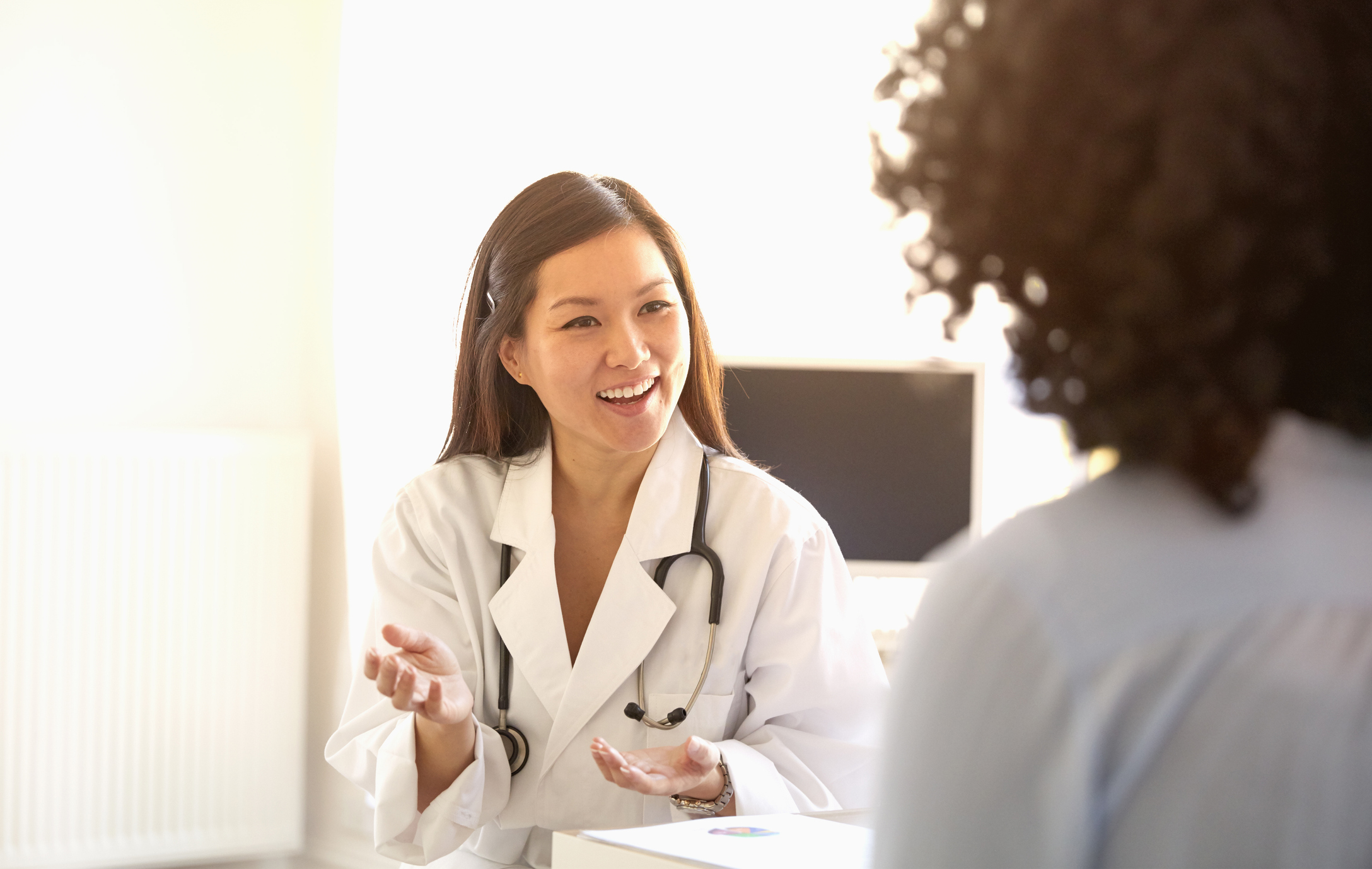 Doctor talking to a patient while ambient clinical intelligence documents the visit